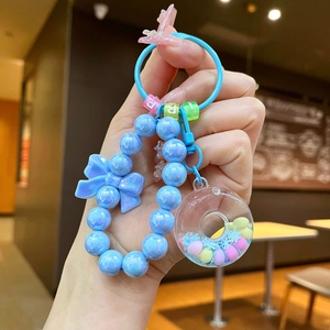 Close-up of blue beaded keyring with glossy bow and colorful transparent charm
