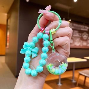 Detail of mint green beaded keychain with colorful donut charm and bow decoration
