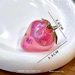 Macro view of a 3D strawberry pendant with pink pearlescent finish and golden leaves