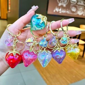 Close-up of colorful resin strawberry keychains with golden leaves and crystal charms