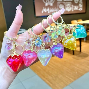 Handheld group of six colorful translucent strawberry keychains with glitter and gold rings