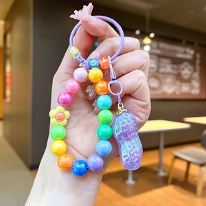 Porte-clés en perles colorées avec fleur et pendentif cacahuète violette tenu en main