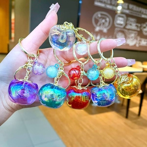 Detailed view of colorful translucent apple keychains held in hand with golden rings