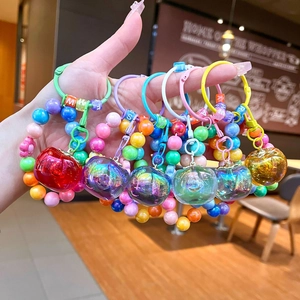 Colorful beaded fruit keychains with iridescent apple charms and letter beads in hand