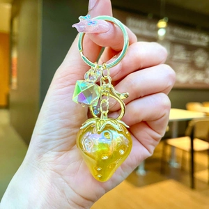 Detail of a yellow transparent resin strawberry keychain with a gold lobster clasp