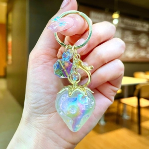 Close-up of aurora strawberry keychain charm with golden leaf and purple bead