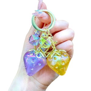 Glittery resin strawberry keychain with purple and yellow charms on gold ring