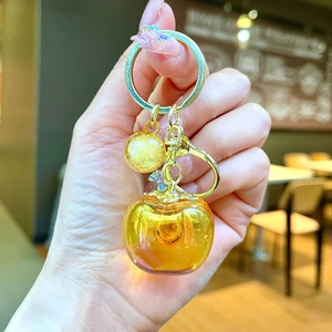Close-up of translucent amber apple resin pendant with a matte gold metallic bead charm