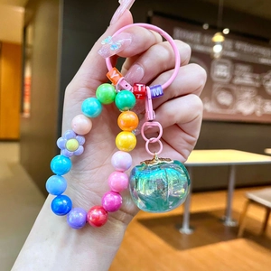 Close-up of a colorful beaded keychain with a translucent green apple pendant charms