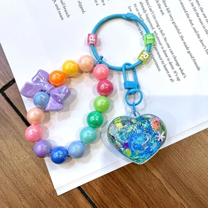 Detailed shot of luminous colorful beaded heart keychain with blue glitter liquid charm