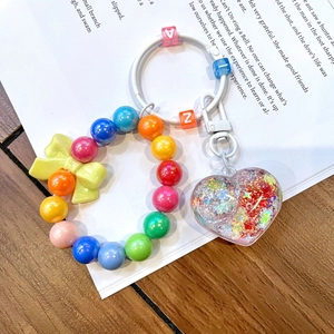 Macro detail of colorful beaded keychain with liquid glitter heart and bow accessory