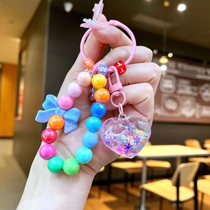 Macro view of luminous heart pendant keychain with colorful beads and blue bow detail