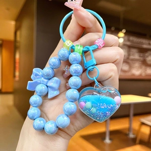 Dettaglio del portachiavi con perline azzurre e ciondolo a cuore luminoso con fiocco