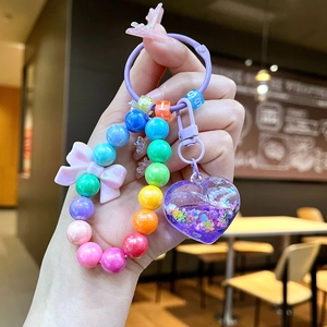 Detailed close-up of rainbow bead keychain with liquid glitter heart and pink bow detail