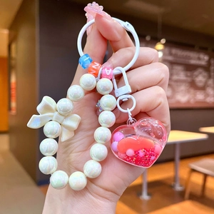 Dettaglio del portachiavi a cuore con sabbia liquida rosa e fiocco bianco decorativo