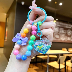 Close-up of heart-shaped keychain with colorful beads and purple ribbon detail