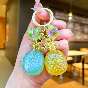 Colorful resin pineapple keychains with golden metal rings and diamond charms in hand