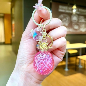 Close-up of pink pineapple charm with gold hardware and butterfly crystal detail