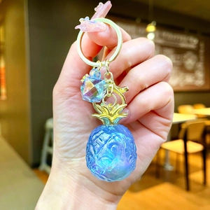 Detailed macro view of a pearlescent gradient pineapple keychain with a crystal charm