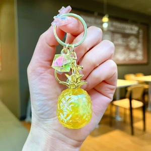 Close-up of translucent yellow resin pineapple pendant with golden metal keyring keychain
