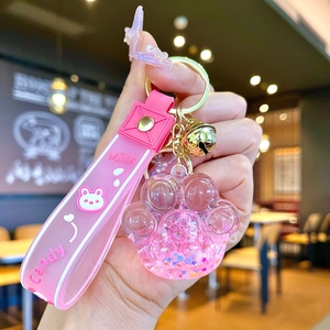 Détail du porte-clés patte de chat avec paillettes liquides et lanière en silicone rose