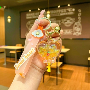 Detail of sweet heart keychain with orange silicone strap and yellow glitter balls