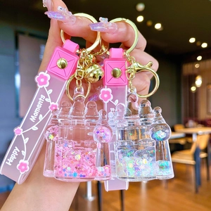 Close-up of castle oil-filled liquid glitter keychain with pink flower hand strap