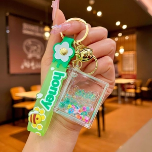 Detail of green silicone lanyard with bee patterns and acrylic oil-filled charm