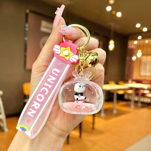 Close-up of pink acrylic floating panda keychain with glitter and gold bell charm
