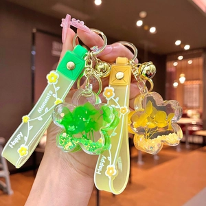 Floral oil-filled acrylic keychain with green and yellow petals and gold bell