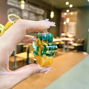 Close-up of handmade resin keychain with green leaves, orange flowers and gold metal hook
