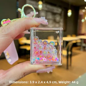 Detail of book-shaped acrylic keychain with colorful quicksand and stars, size 3.9x4.9cm