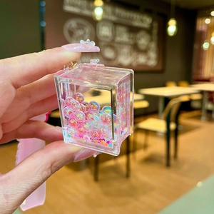 Detail shot of a book-shaped acrylic keychain with pink quicksand glitter and stars