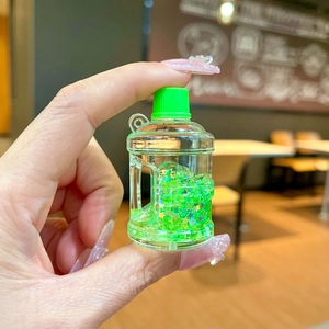 Close-up of green bucket-shaped keychain featuring liquid glitter and star-shaped sequins