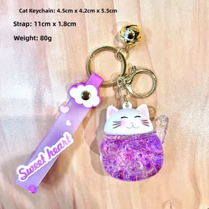 Detail of purple Lucky Cat keychain with liquid glitter sand and violet wrist strap