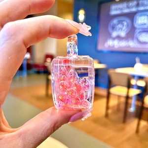 Detail of a transparent rectangular keychain filled with pink sparkling liquid and glitters