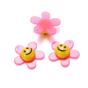 Macro detail of pink acrylic flower beads with yellow smiley face center for DIY crafts