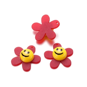 Macro detail of red matte acrylic sunflower charms with yellow smiley face center