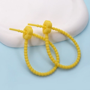 Close-up of yellow silicone cable ties with flower buckles on a white stone pedestal