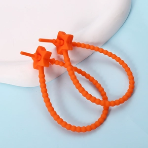 Macro view of bright orange star-shaped silicone earrings on a white stand