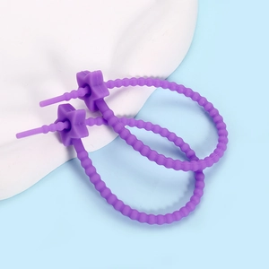 Close-up of adjustable purple silicone star cable ties on a white stone background