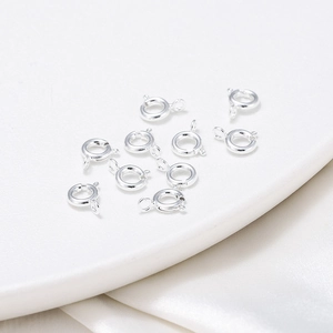 Macro shot of silver-colored spring ring clasps for jewelry making on white silk