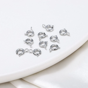 Assorted silver spring ring clasps for jewelry making displayed on a white tray