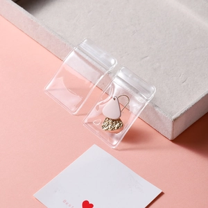 Close-up of thick transparent PVC jewelry bag with a pink pendant earring inside