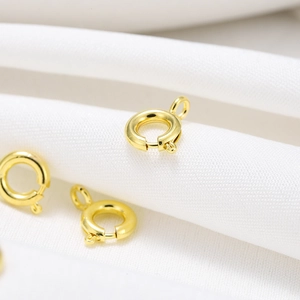 Close-up of 18K gold-plated spring ring clasps for jewelry making on white fabric
