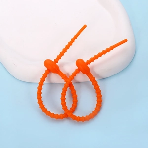 Macro detail of adjustable orange silicone cable ties with gear-lock design for wire storage