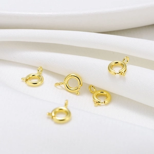 Macro shot of 18K gold plated spring ring clasps on white textured fabric background