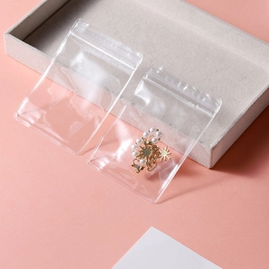 Close-up of clear PVC self-sealing jewelry bag storing a gold star pearl earring