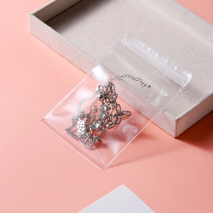 Macro shot of silver-colored layered necklace with star charms in a clear PVC seal bag