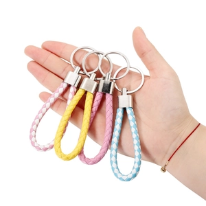 Close-up of four colorful woven leather keychains with metallic rings held in hand